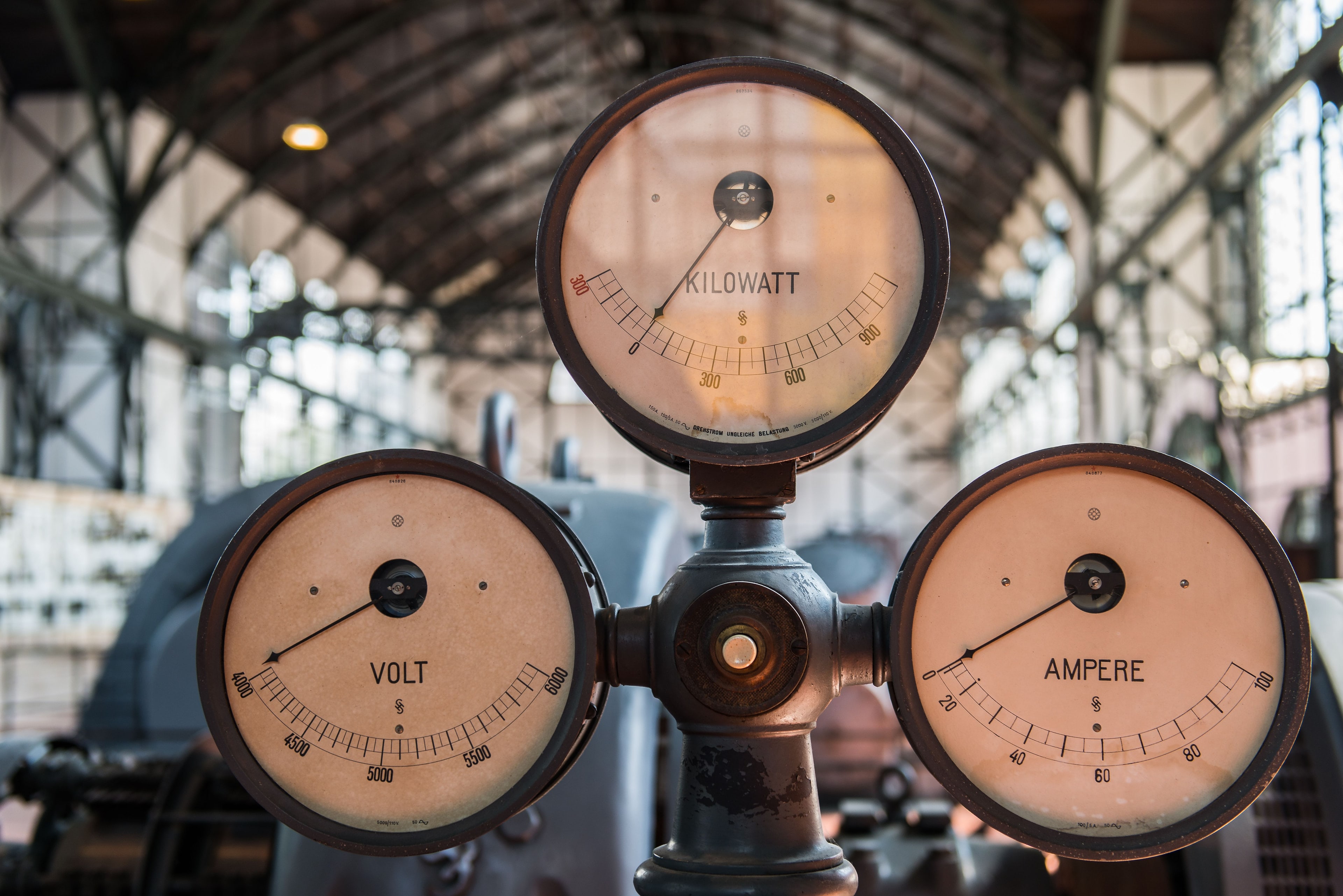 Trois cadrans anciens de kilowatts, de volts et d'ampères dans une salle des machines.