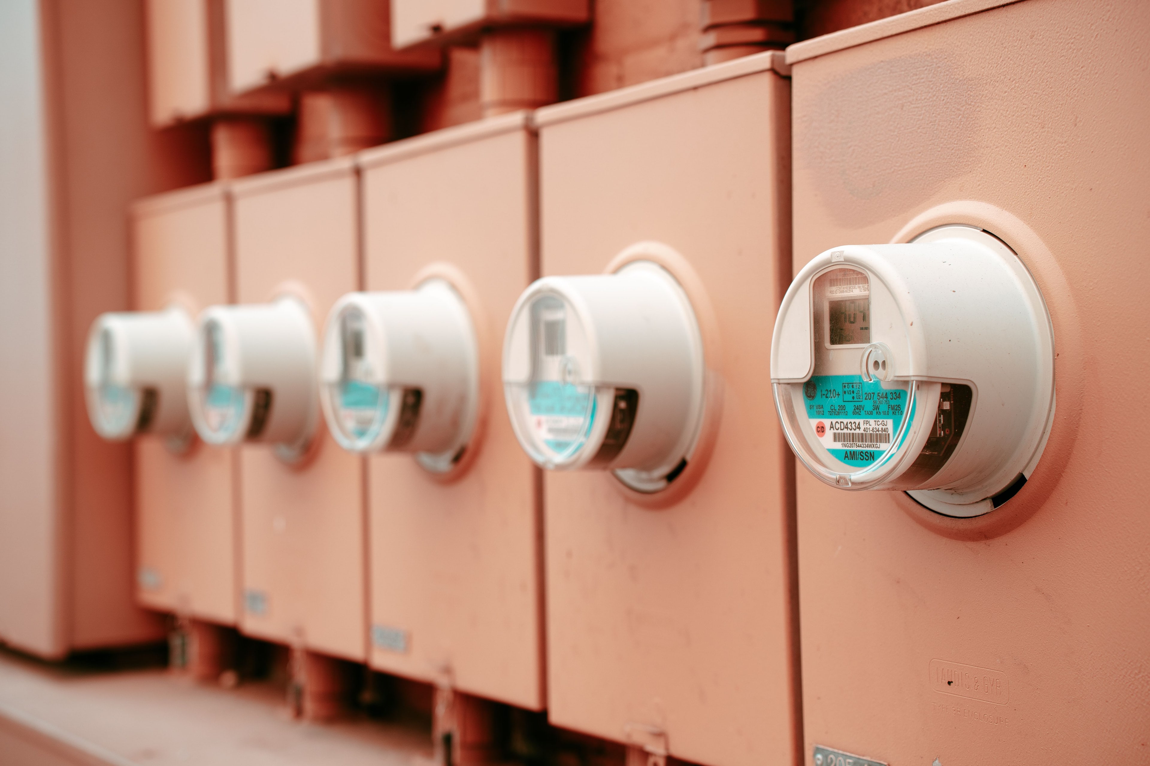 Rangée de compteurs électriques sur des coffrets alignés.