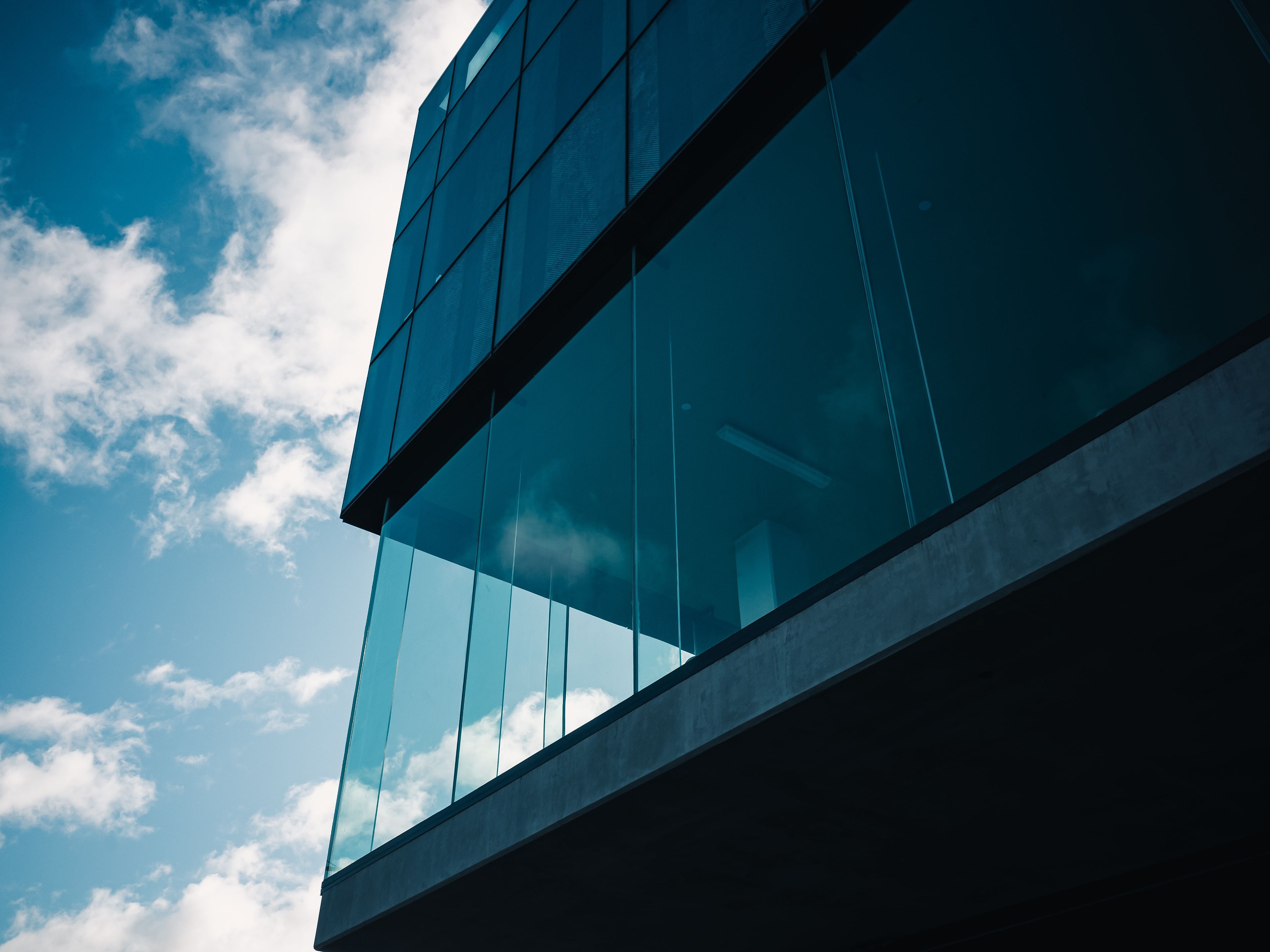 Façade de verre sombre vue d'en bas, nuages reflétés.